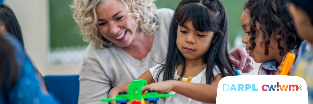 Child plays with toys while adult supports