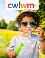 Child wearing green sunglasses blowing bubbles